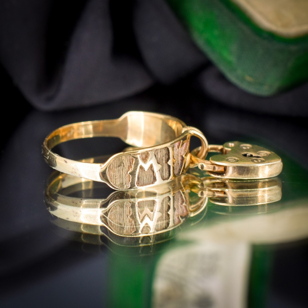 A vintage 9ct yellow gold band ring featuring relief MIZPAH lettering and a dangling heart padlock charm. View IV