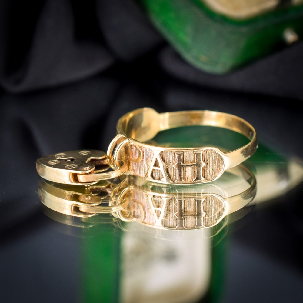 A vintage 9ct yellow gold band ring featuring relief MIZPAH lettering and a dangling heart padlock charm. View VII