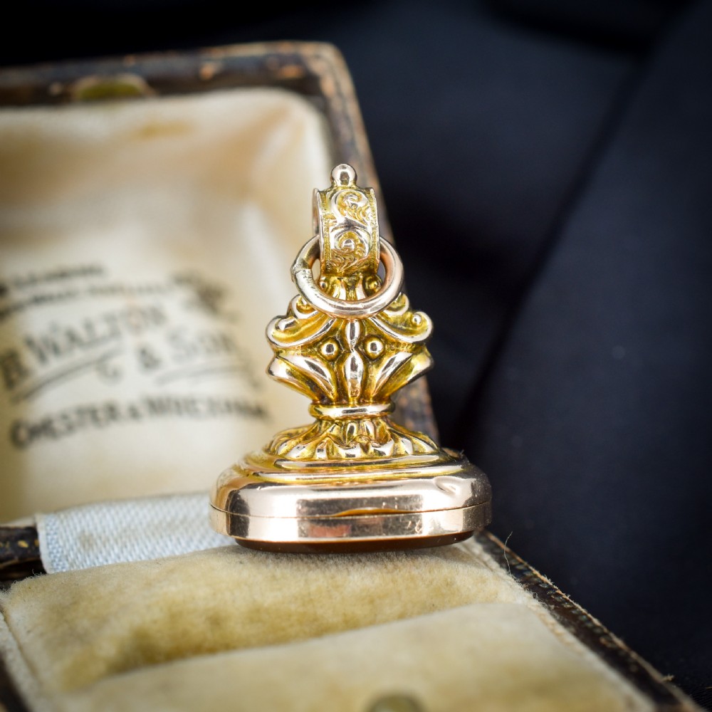 An Edwardian 9ct gold fob featuring chased scrollwork, a top suspension ring, and a carnelian seal base.