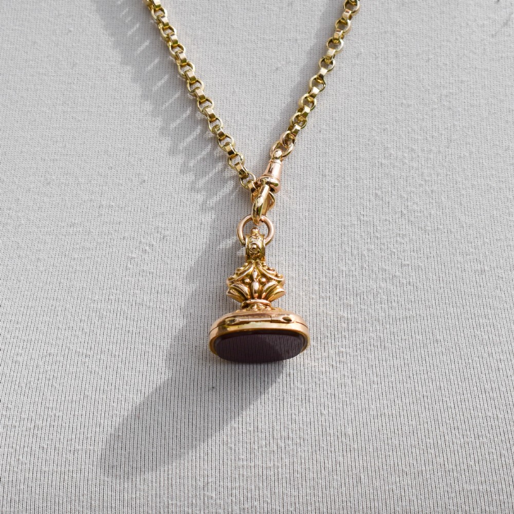 An Edwardian 9ct gold fob featuring chased scrollwork, a top suspension ring, and a carnelian seal base. View X