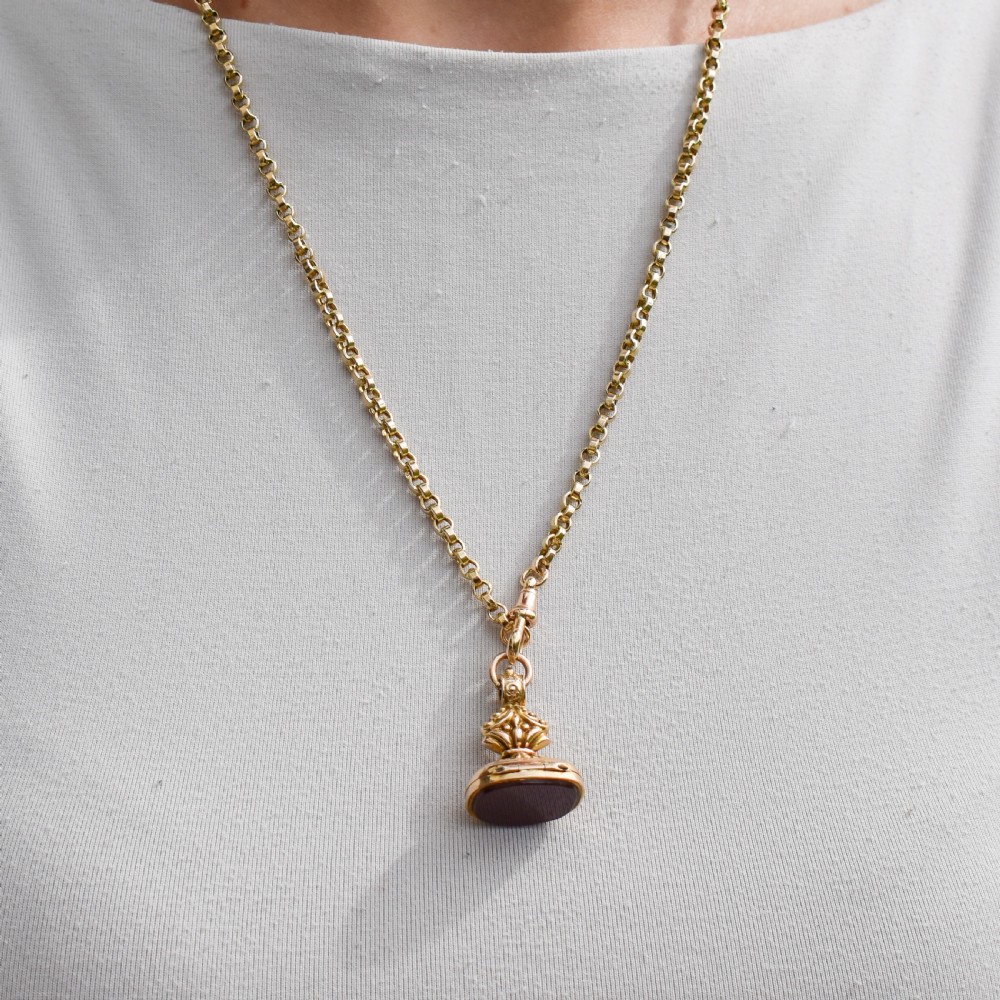 An Edwardian 9ct gold fob featuring chased scrollwork, a top suspension ring, and a carnelian seal base. View XI