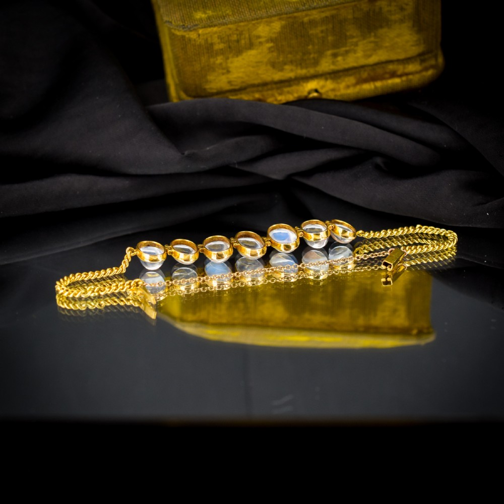 An antique 18ct gold link bracelet set with seven graduating oval moonstone cabochons. View VII