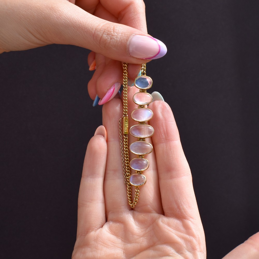An antique 18ct gold link bracelet set with seven graduating oval moonstone cabochons. View VIII