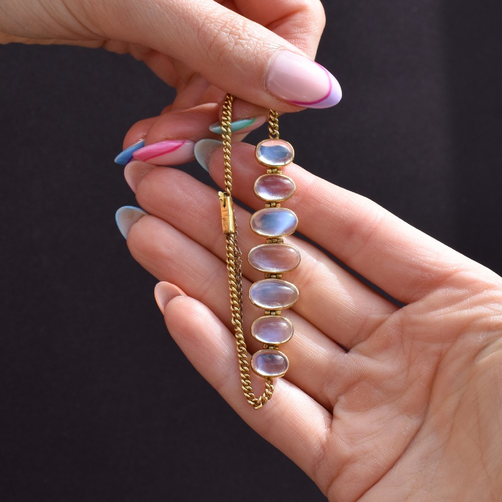 An antique 18ct gold link bracelet set with seven graduating oval moonstone cabochons. View IX
