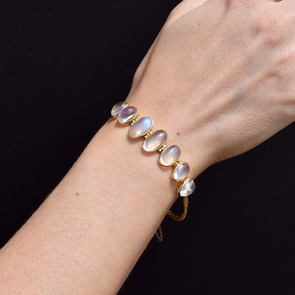 An antique 18ct gold link bracelet set with seven graduating oval moonstone cabochons. View X