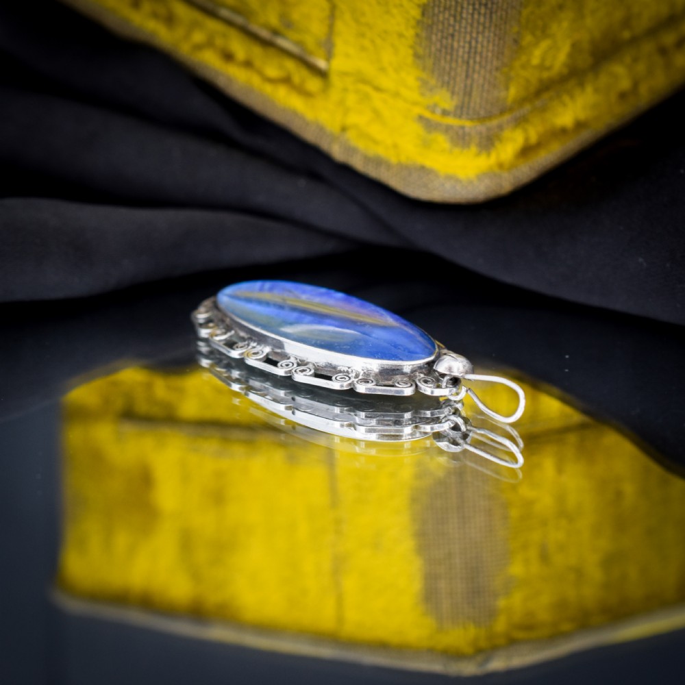 An elongated oval sterling silver Art Deco pendant enclosing a vivid blue butterfly wing with a scrolled wirework outer frame. View II