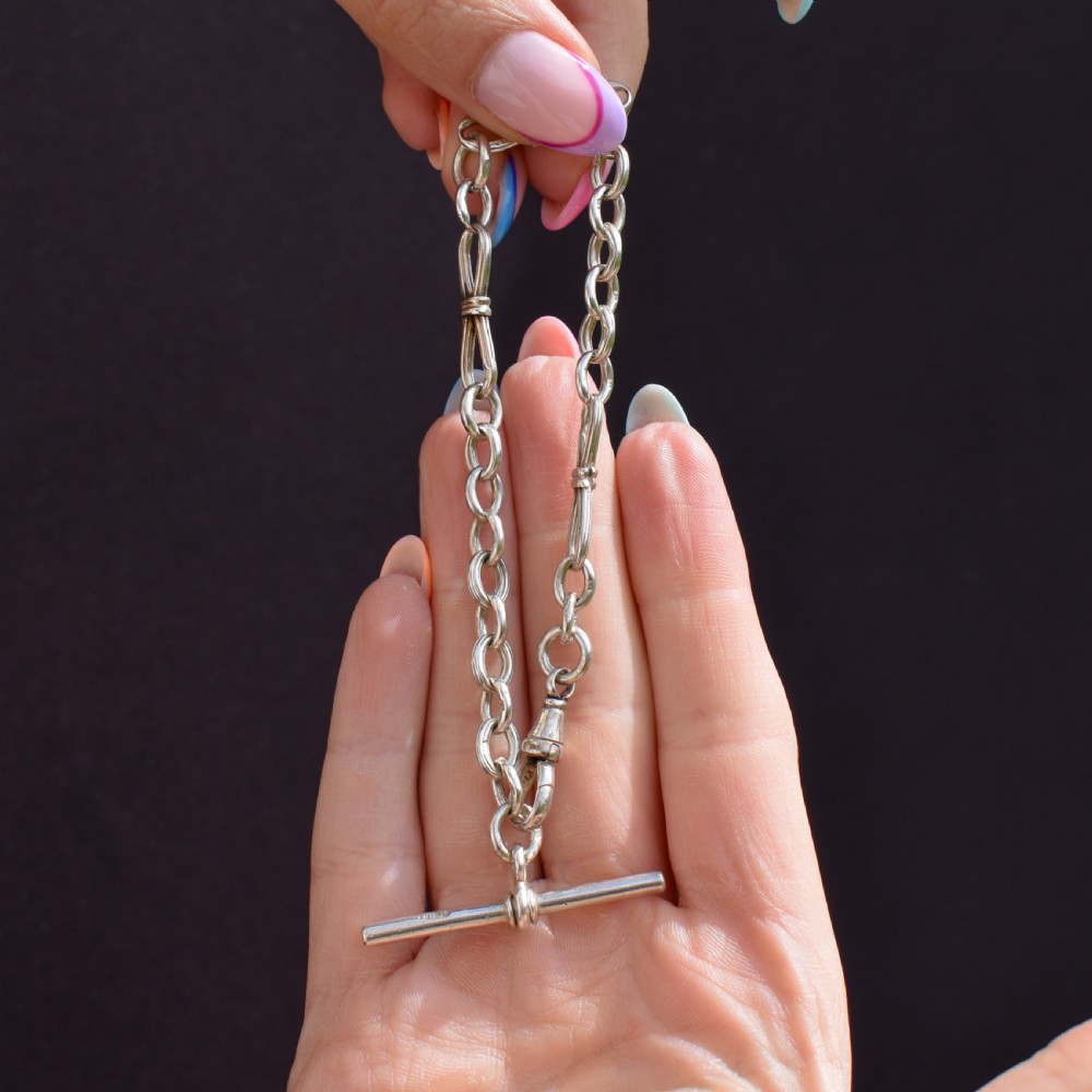 An antique sterling silver fancy link chain bracelet featuring a dog clip fastener and a suspended T-bar drop. View VII