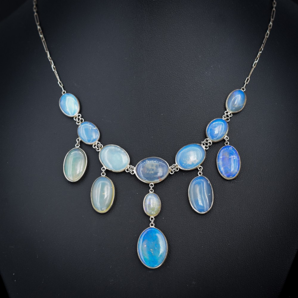 An Edwardian silver festoon necklace featuring graduated oval cabochon opals arranged in hanging fringe drops.