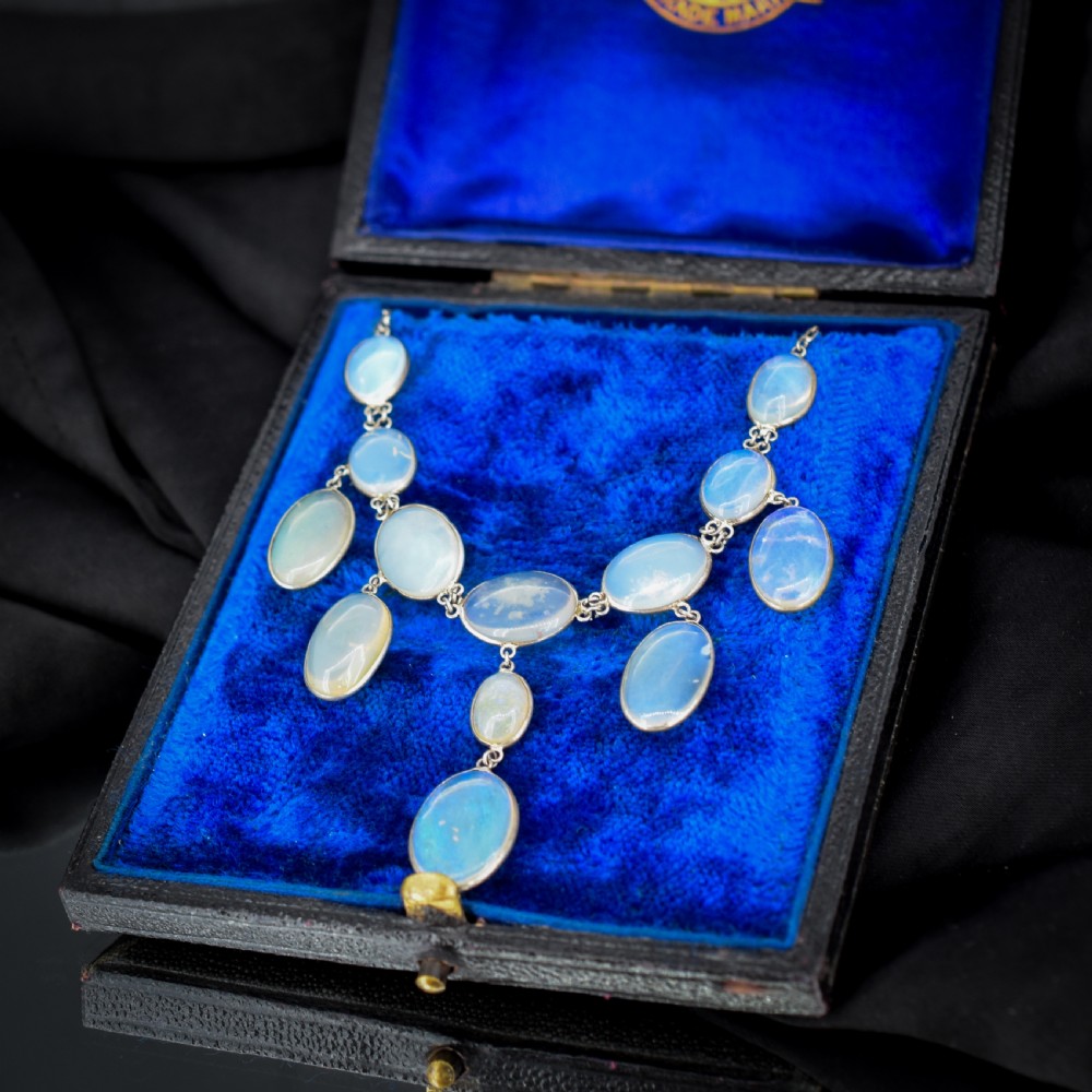 An Edwardian silver festoon necklace featuring graduated oval cabochon opals arranged in hanging fringe drops. View IV