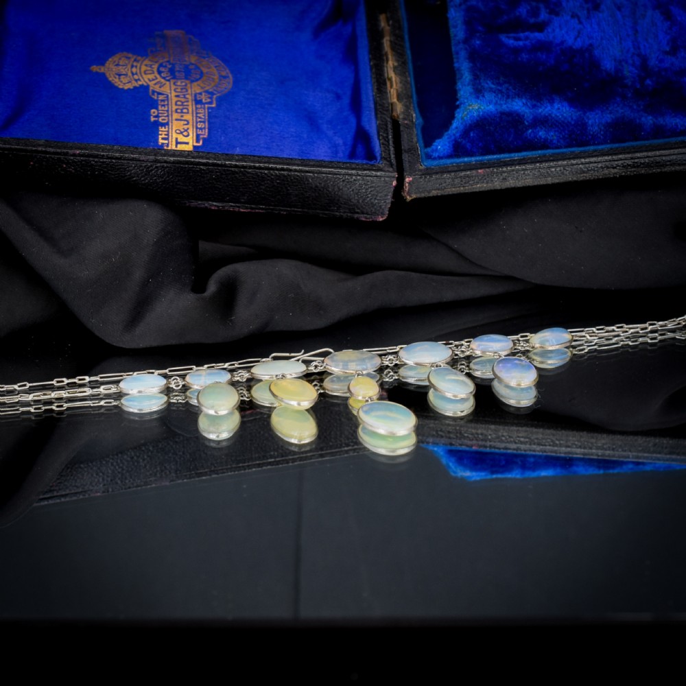 An Edwardian silver festoon necklace featuring graduated oval cabochon opals arranged in hanging fringe drops. View VII