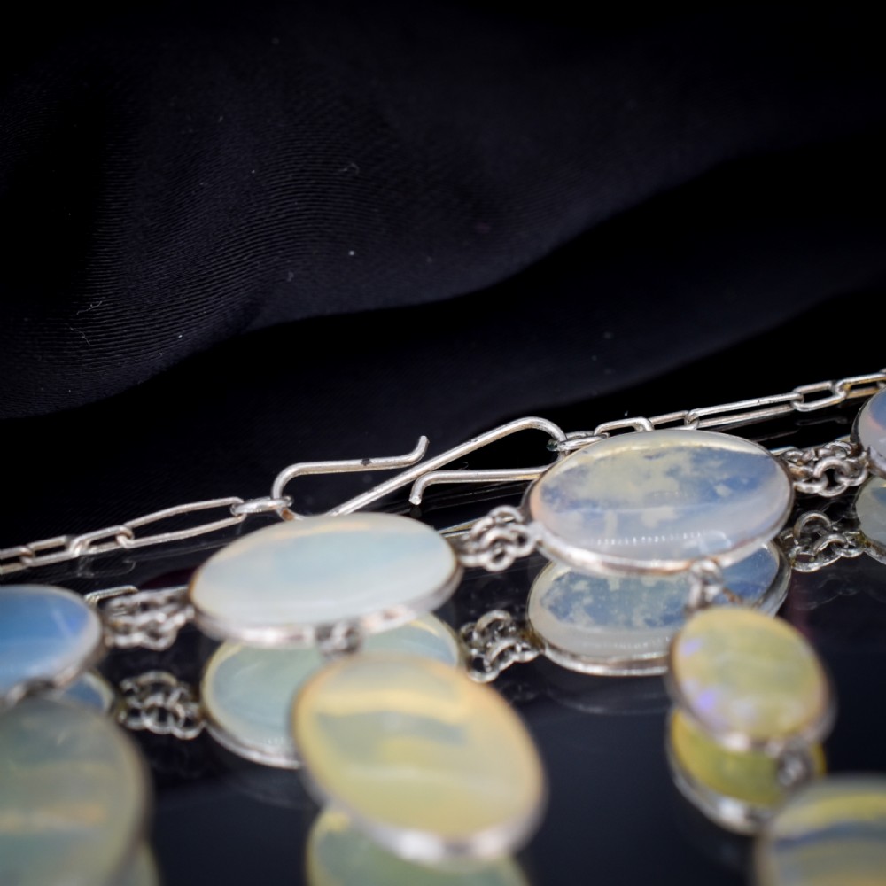 An Edwardian silver festoon necklace featuring graduated oval cabochon opals arranged in hanging fringe drops. View VIII