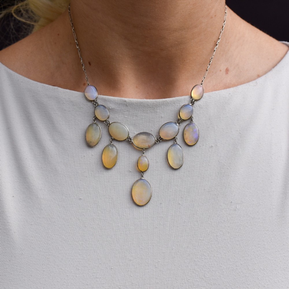 An Edwardian silver festoon necklace featuring graduated oval cabochon opals arranged in hanging fringe drops. View IX