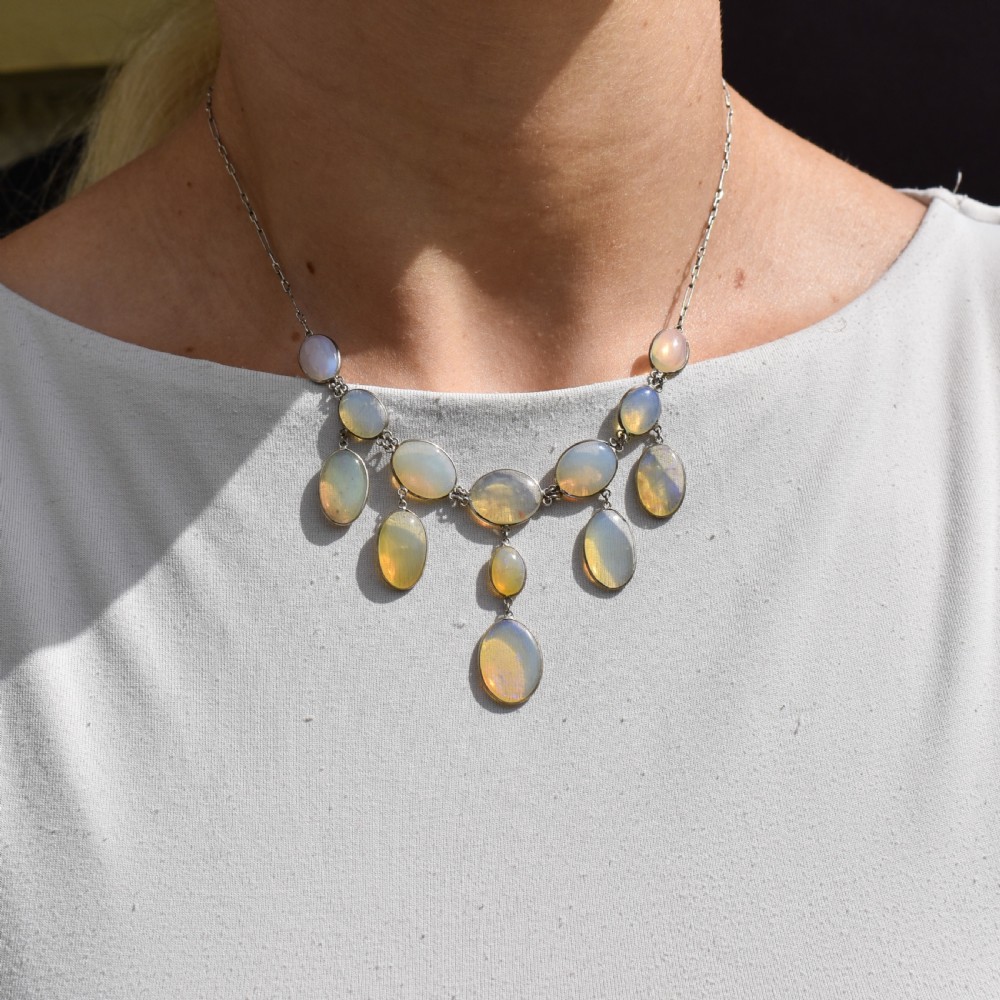 An Edwardian silver festoon necklace featuring graduated oval cabochon opals arranged in hanging fringe drops. View X