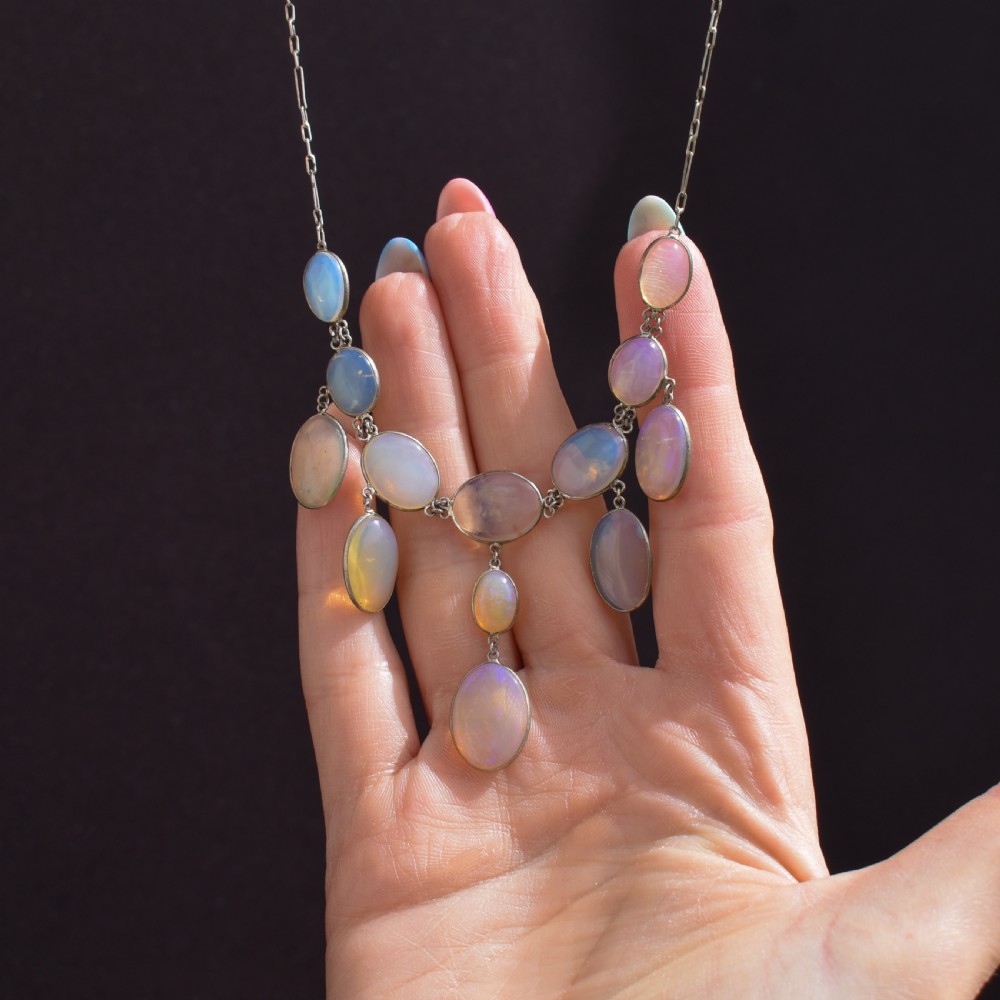 An Edwardian silver festoon necklace featuring graduated oval cabochon opals arranged in hanging fringe drops. View XII