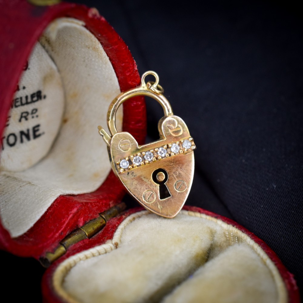 An antique 9ct yellow gold heart-shaped padlock charm set with a row of small round diamonds across the centre bar and featuring an engraved keyhole design. View III