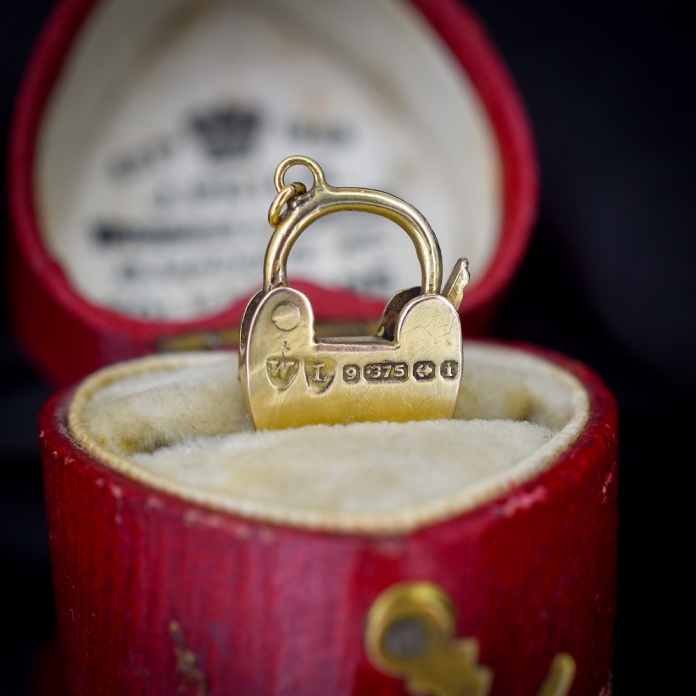 An antique 9ct yellow gold heart-shaped padlock charm set with a row of small round diamonds across the centre bar and featuring an engraved keyhole design. View IV