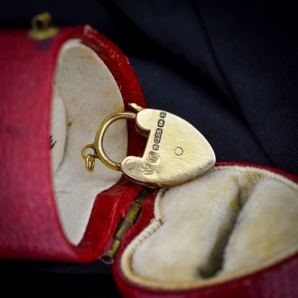 An antique 9ct yellow gold heart-shaped padlock charm set with a row of small round diamonds across the centre bar and featuring an engraved keyhole design. View V