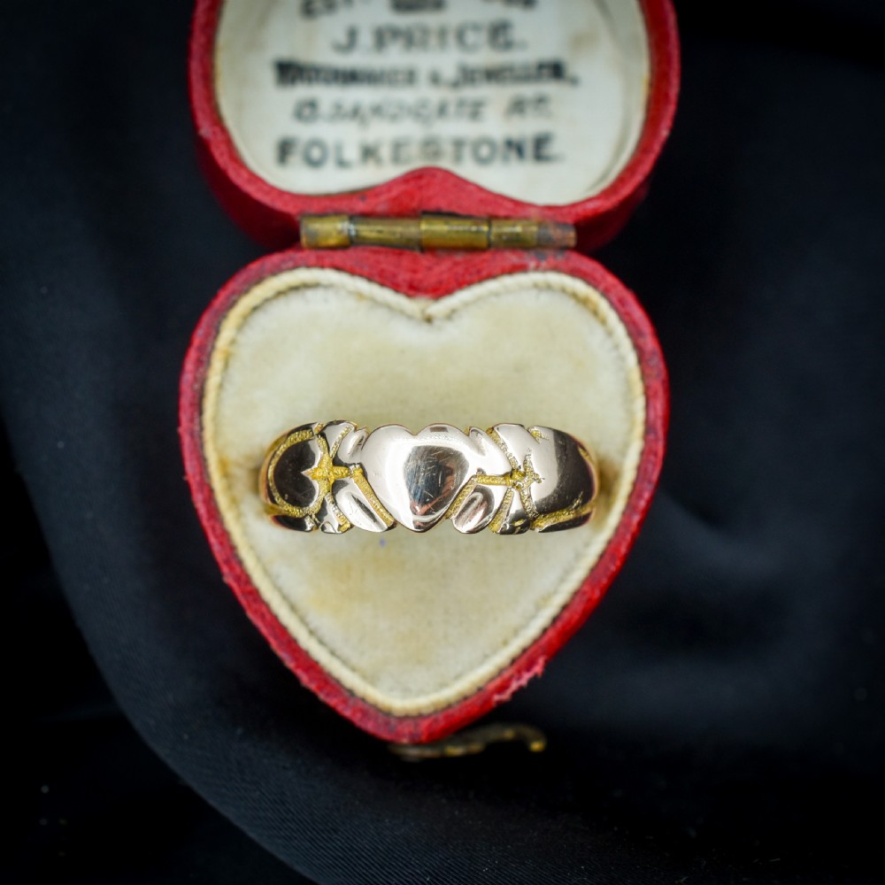 An antique Victorian 9ct yellow gold band ring featuring polished heart motifs set against textured background detailing. View II