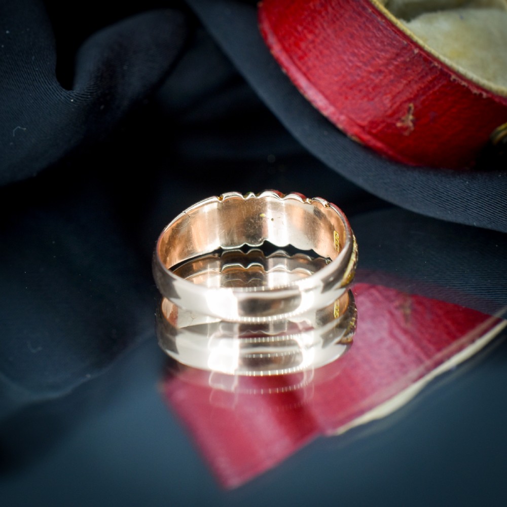 An antique Victorian 9ct yellow gold band ring featuring polished heart motifs set against textured background detailing. View VI