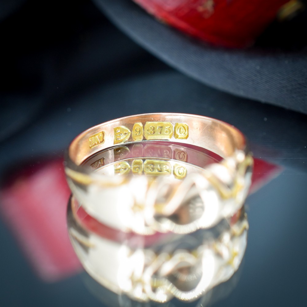 An antique Victorian 9ct yellow gold band ring featuring polished heart motifs set against textured background detailing. View VIII