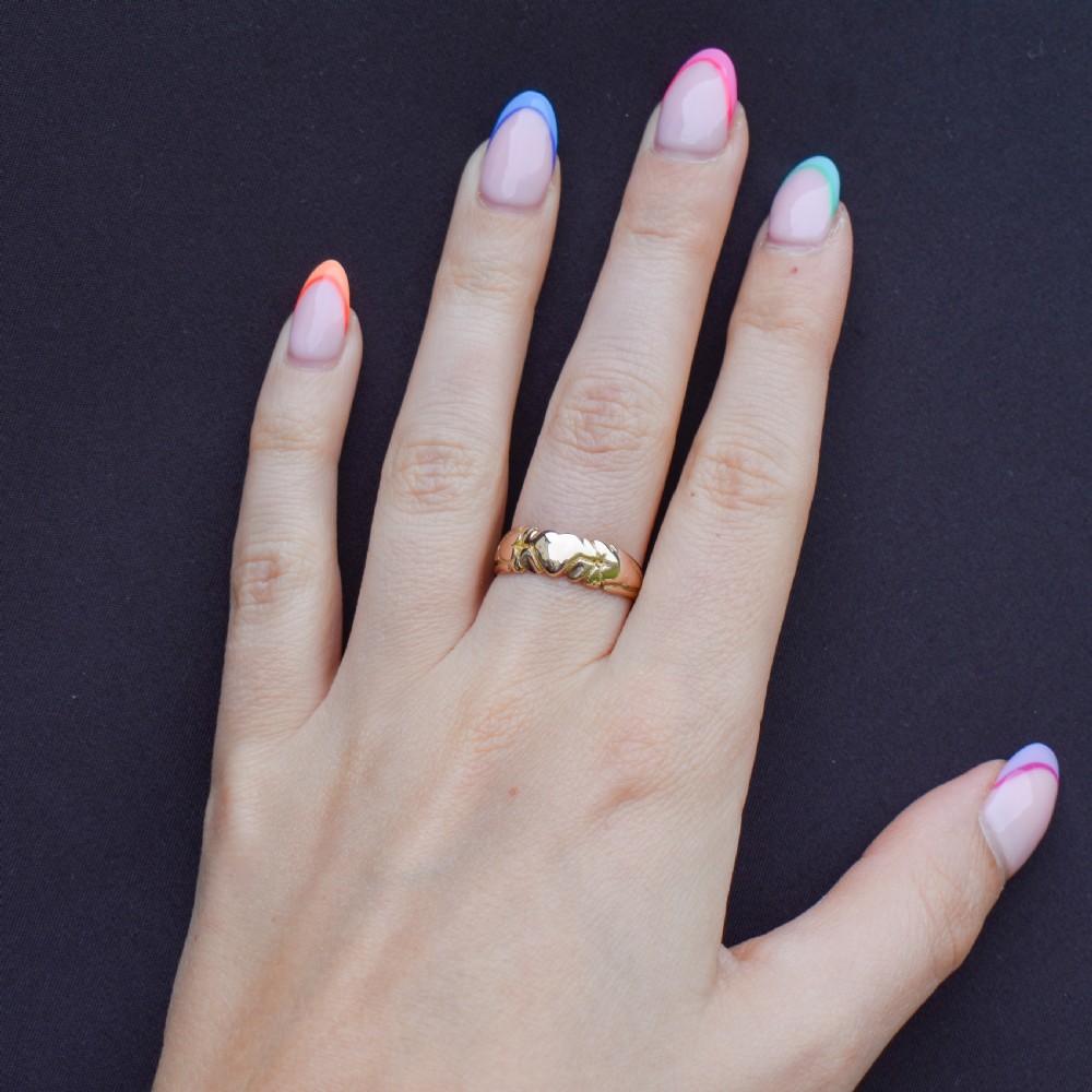 An antique Victorian 9ct yellow gold band ring featuring polished heart motifs set against textured background detailing. View X