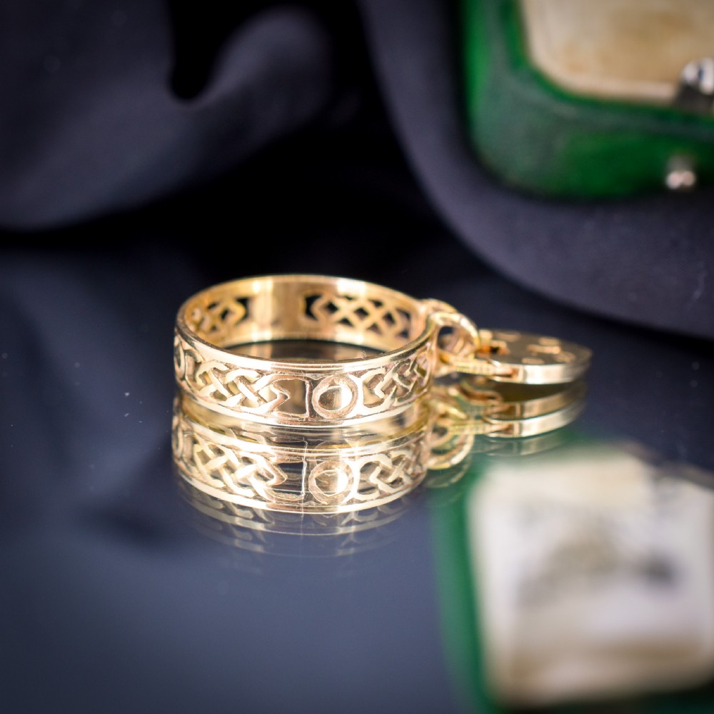 A 9ct yellow gold band ring featuring an openwork Celtic knot design with a suspended heart-shaped padlock charm at the front. View III