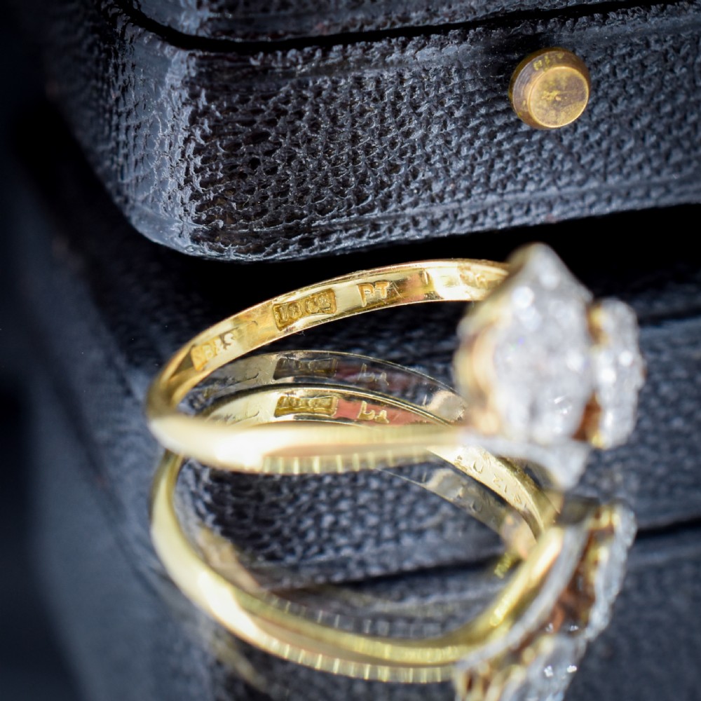 An antique 18ct yellow gold ring with a double twist band featuring two diamond-set flower clusters. View V
