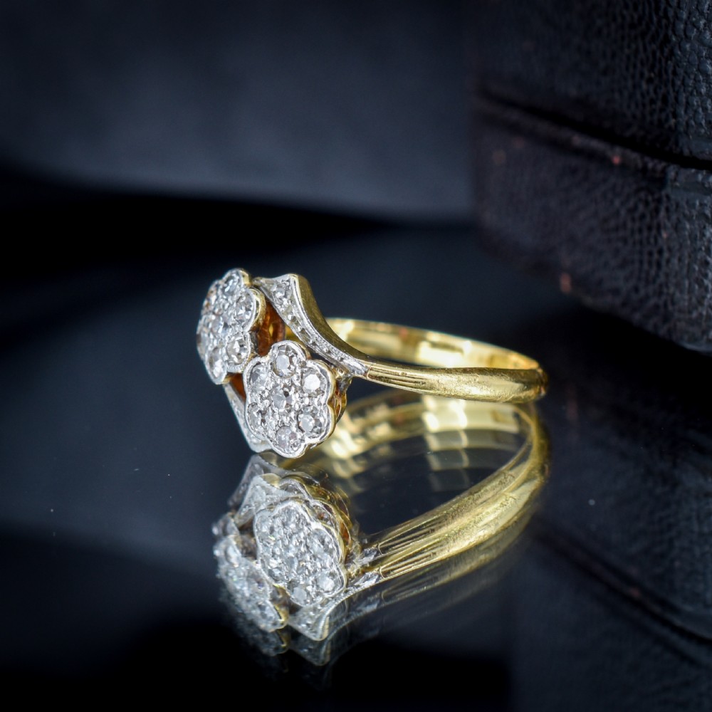 An antique 18ct yellow gold ring with a double twist band featuring two diamond-set flower clusters. View VI