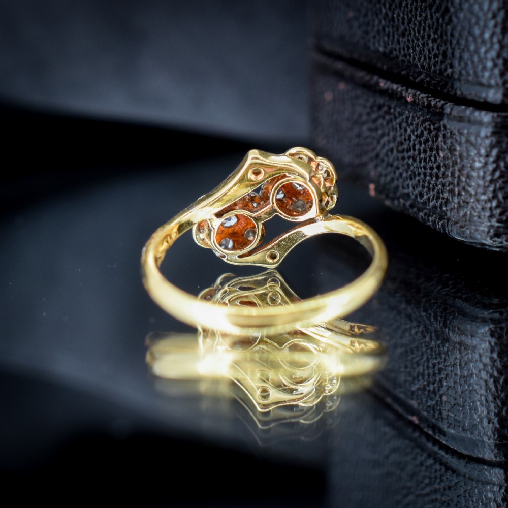 An antique 18ct yellow gold ring with a double twist band featuring two diamond-set flower clusters. View VII