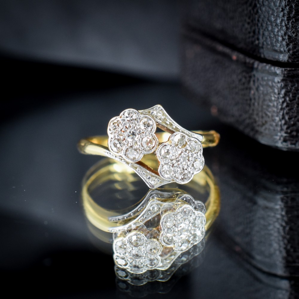 An antique 18ct yellow gold ring with a double twist band featuring two diamond-set flower clusters. View VIII