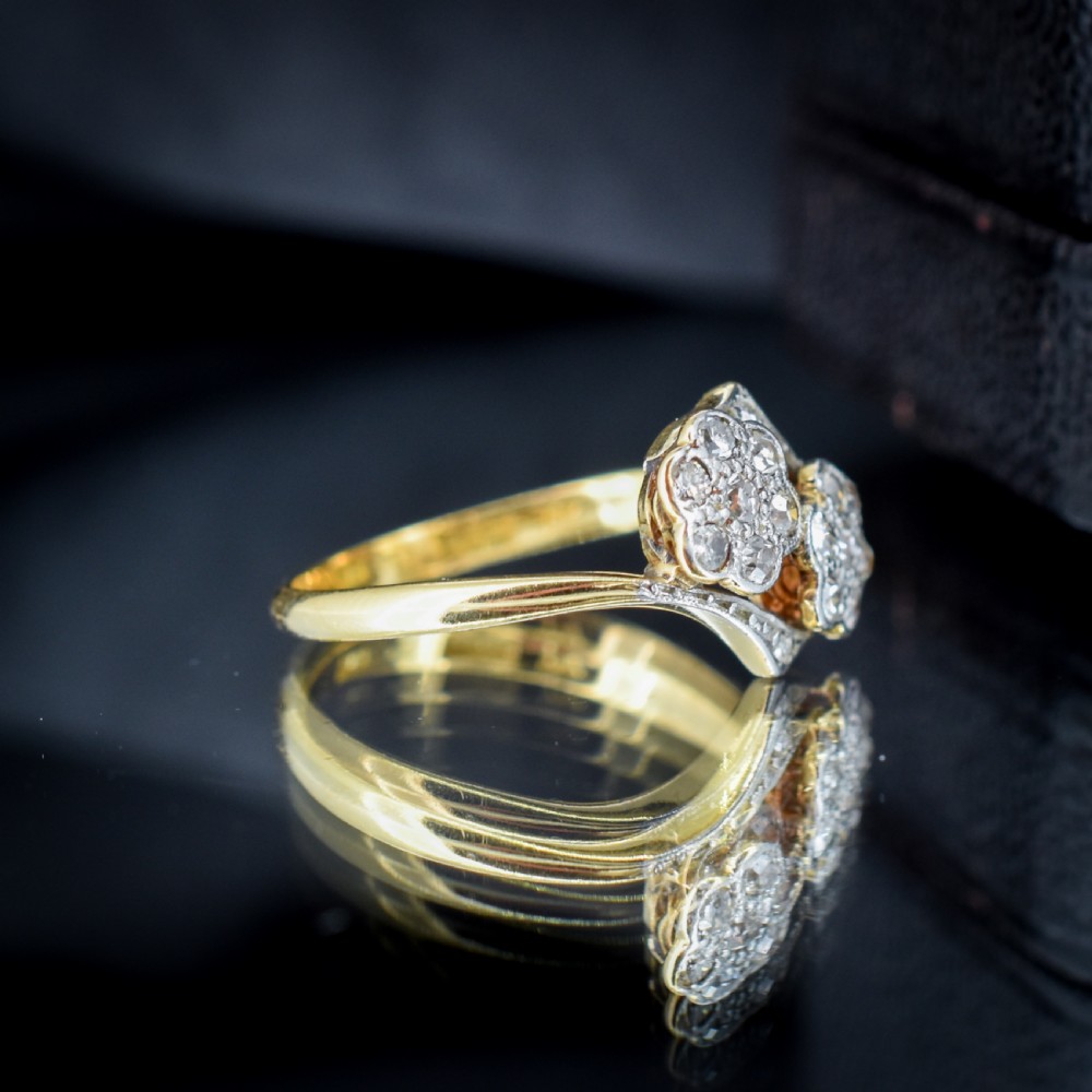 An antique 18ct yellow gold ring with a double twist band featuring two diamond-set flower clusters. View IX