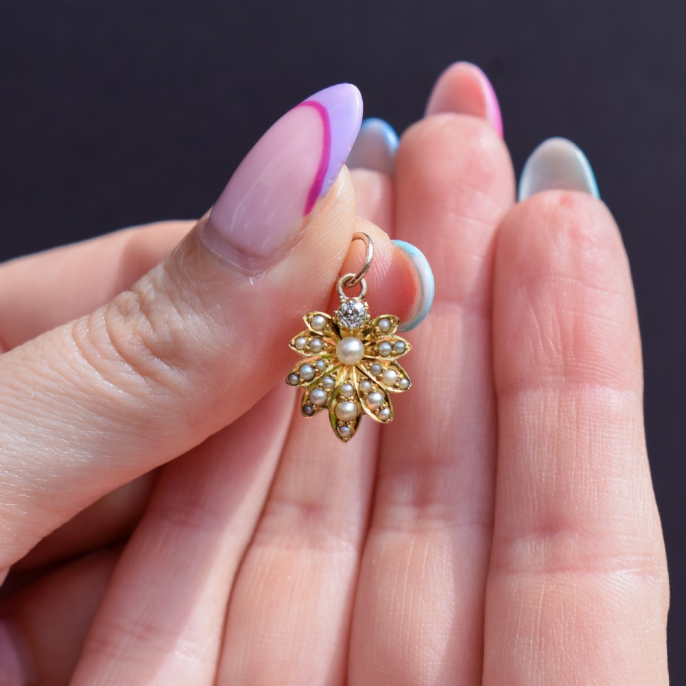 An antique floral gold pendant featuring a central pearl surrounded by seed pearl petals and topped with an old-cut diamond. View III