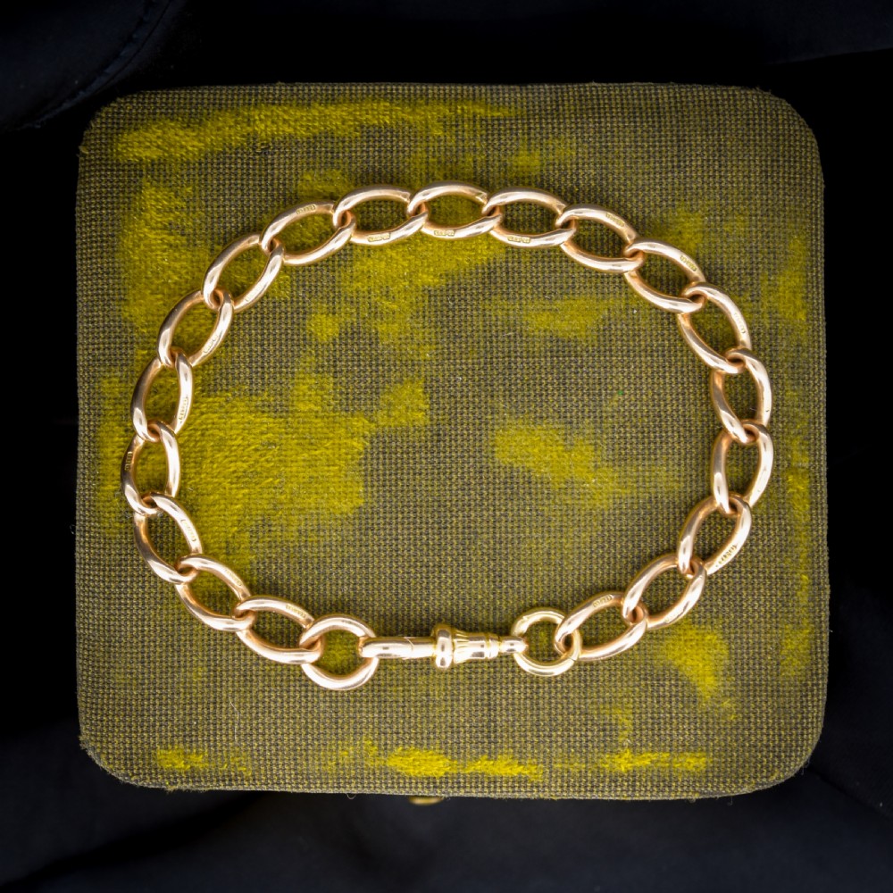 An antique 15ct warm gold oval curb link bracelet featuring stamped links and a dog clip swivel clasp.