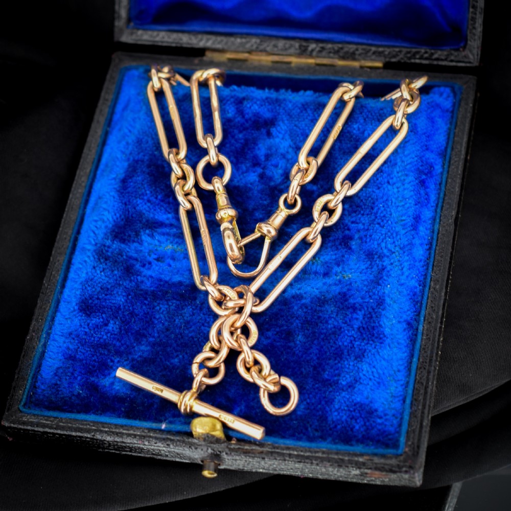 An antique 9ct yellow gold Albert watch chain featuring elongated trombone links, connector rings, a T-bar, and a swivel clasp.