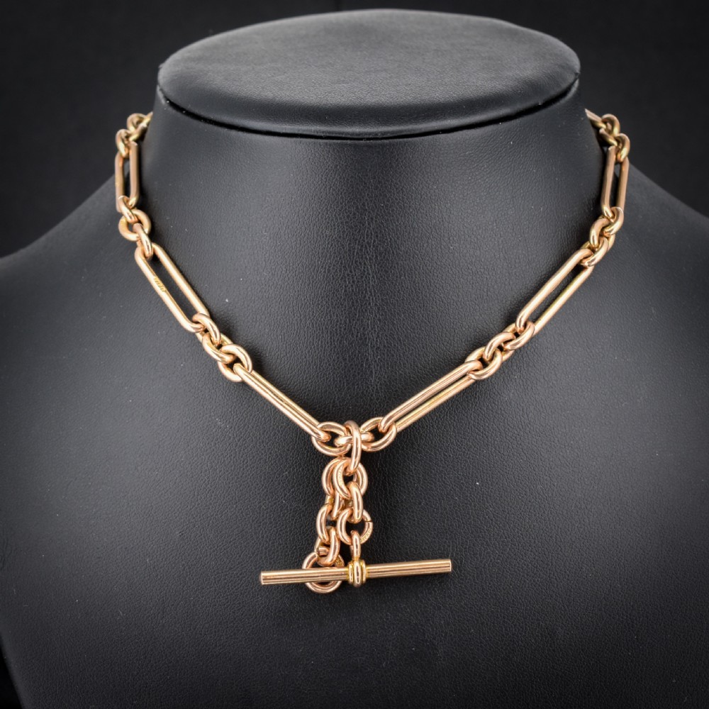 An antique 9ct yellow gold Albert watch chain featuring elongated trombone links, connector rings, a T-bar, and a swivel clasp. View IV