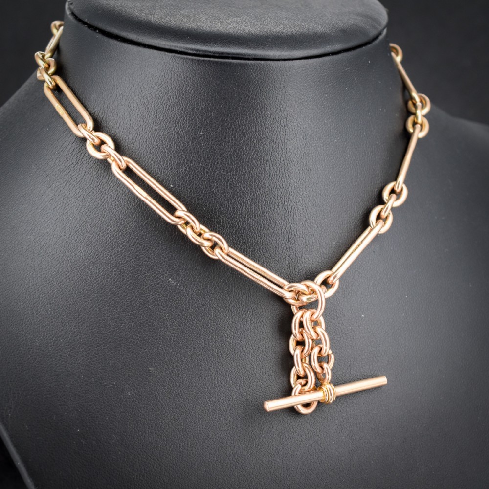 An antique 9ct yellow gold Albert watch chain featuring elongated trombone links, connector rings, a T-bar, and a swivel clasp. View V