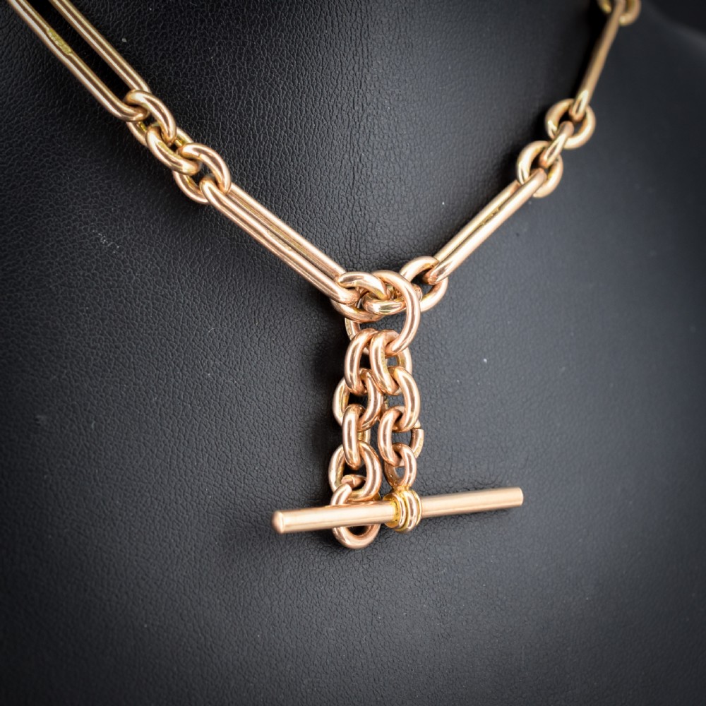 An antique 9ct yellow gold Albert watch chain featuring elongated trombone links, connector rings, a T-bar, and a swivel clasp. View VI