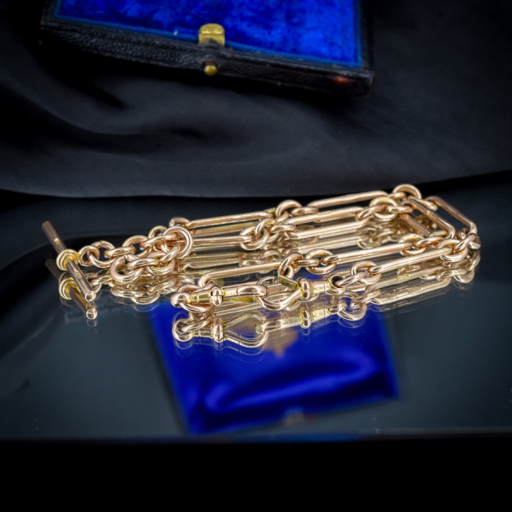 An antique 9ct yellow gold Albert watch chain featuring elongated trombone links, connector rings, a T-bar, and a swivel clasp. View IX
