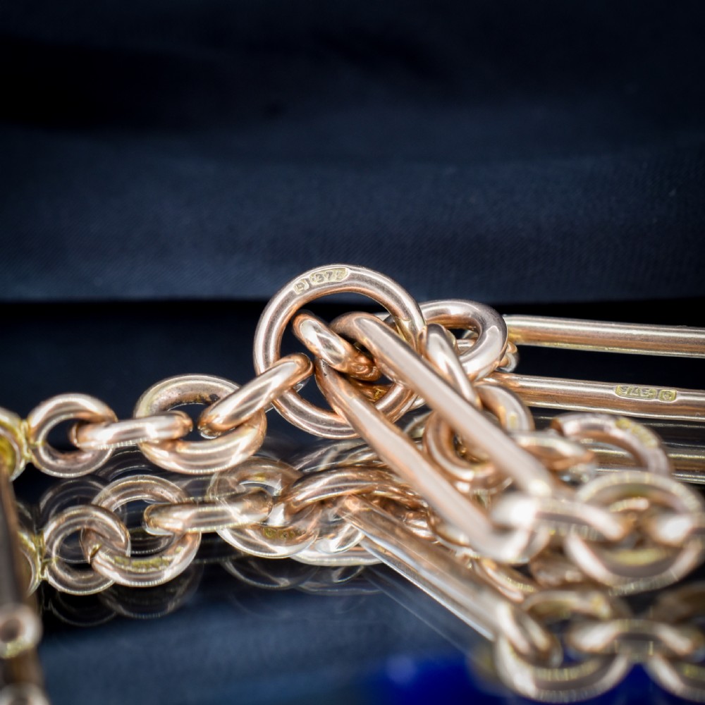 An antique 9ct yellow gold Albert watch chain featuring elongated trombone links, connector rings, a T-bar, and a swivel clasp. View XIII