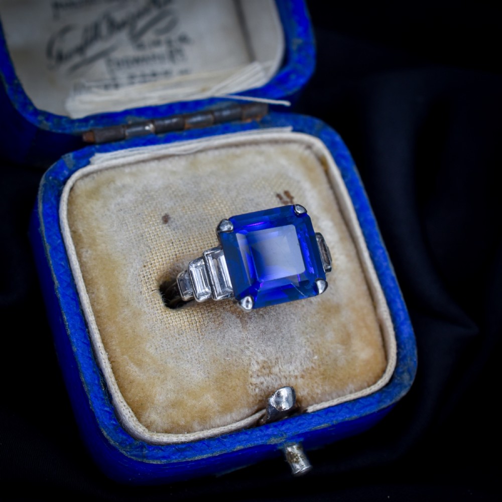 An Art Deco sterling silver cocktail ring set with a large square-cut blue gemstone and stepped baguette-cut side stones. View II