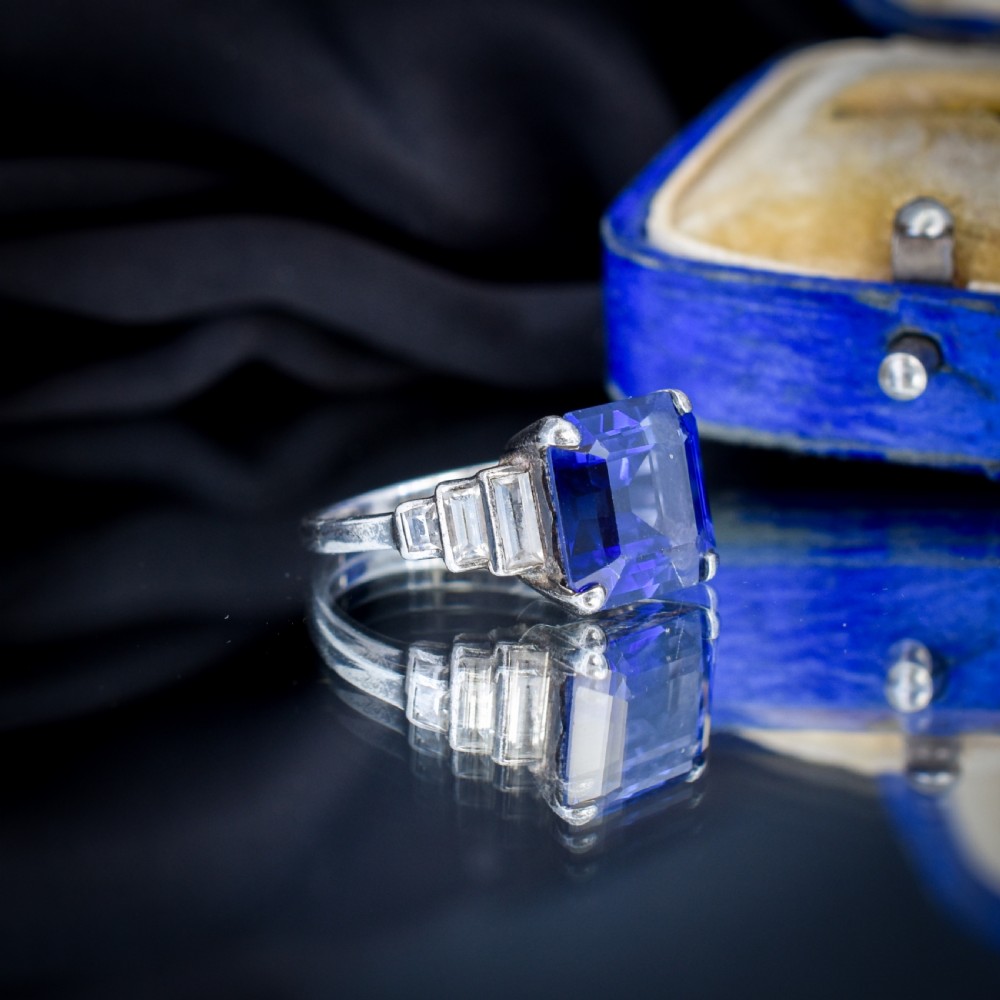 An Art Deco sterling silver cocktail ring set with a large square-cut blue gemstone and stepped baguette-cut side stones. View V