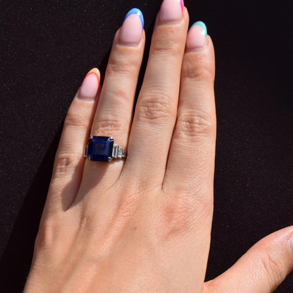 An Art Deco sterling silver cocktail ring set with a large square-cut blue gemstone and stepped baguette-cut side stones. View X