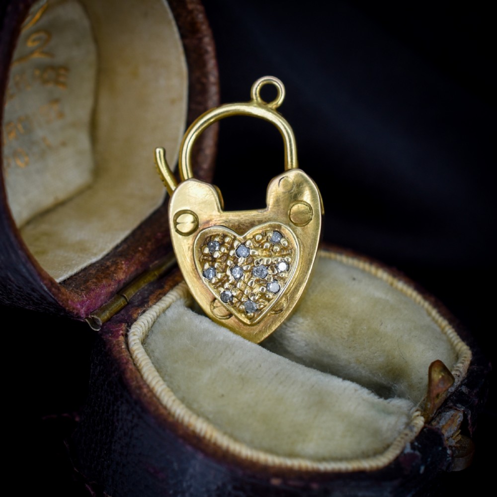 An Edwardian 9ct yellow gold heart-shaped padlock charm featuring a pave diamond centre and a hinged top arch.