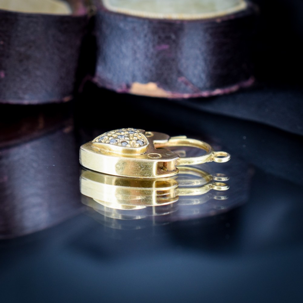 An Edwardian 9ct yellow gold heart-shaped padlock charm featuring a pave diamond centre and a hinged top arch. View VI
