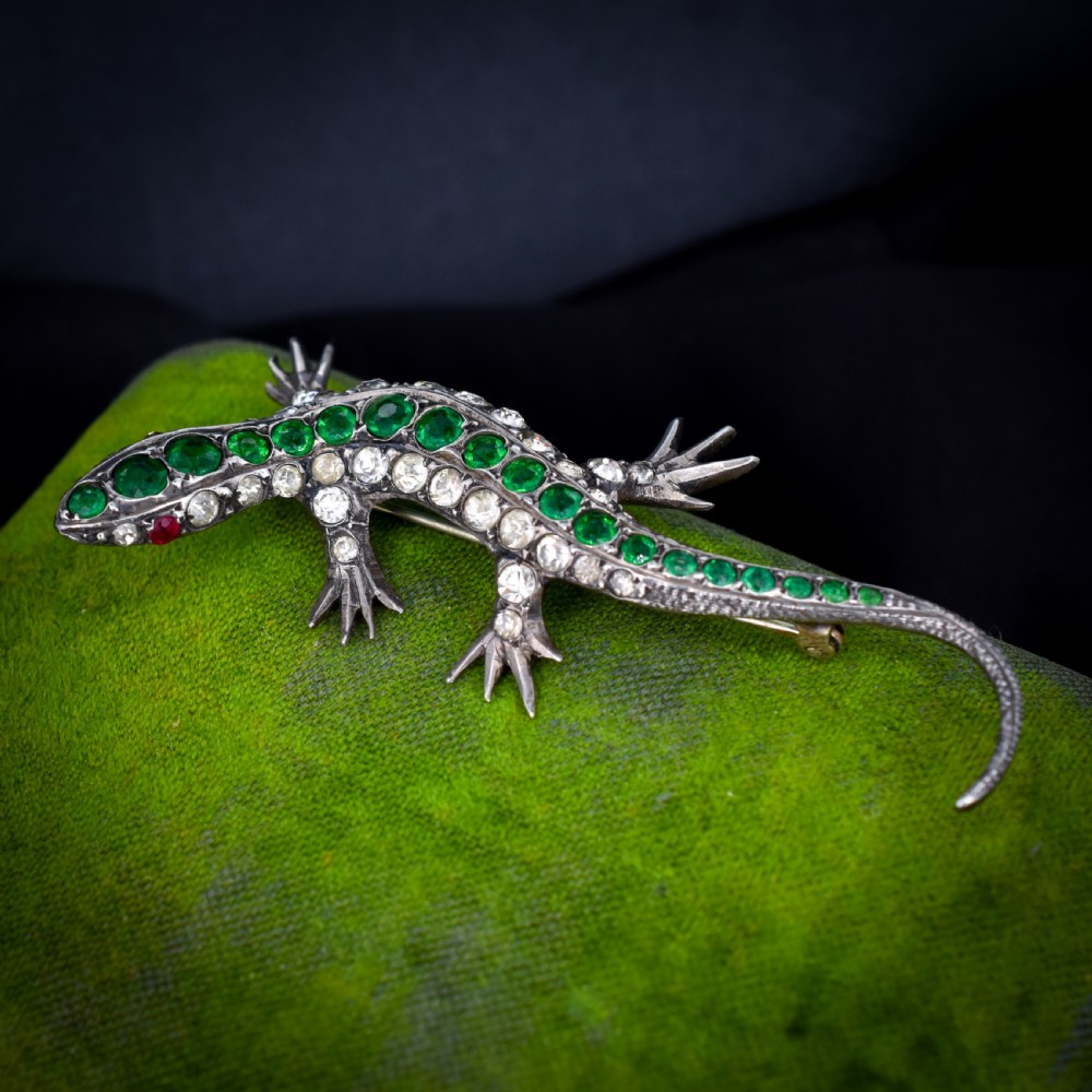 An antique Victorian silver lizard brooch set with a row of green paste stones along the spine and clear paste stones along the outer body. View III