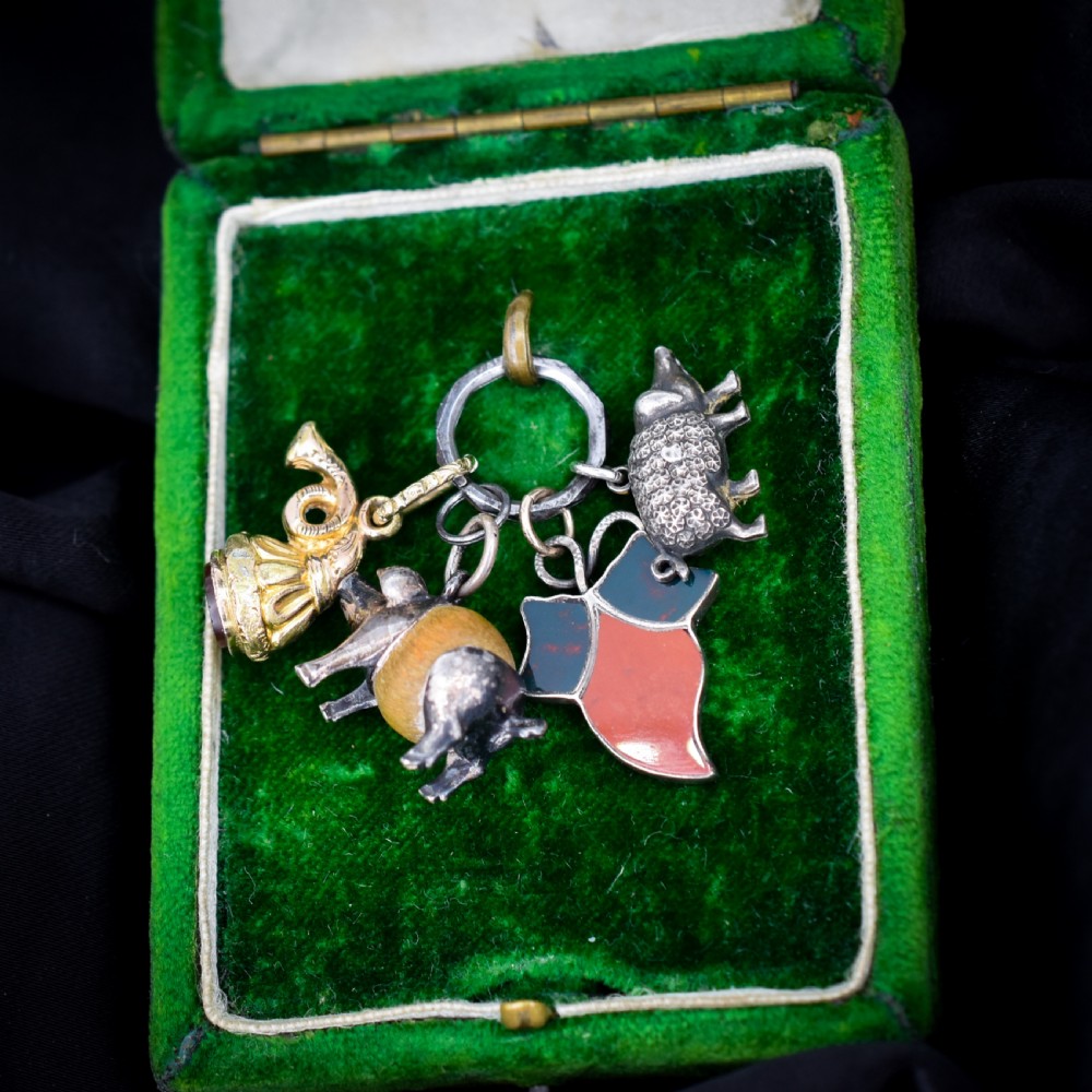 A cluster of antique silver and gold-gilt novelty charms, including pigs and a bugle, attached to a central metal split ring.