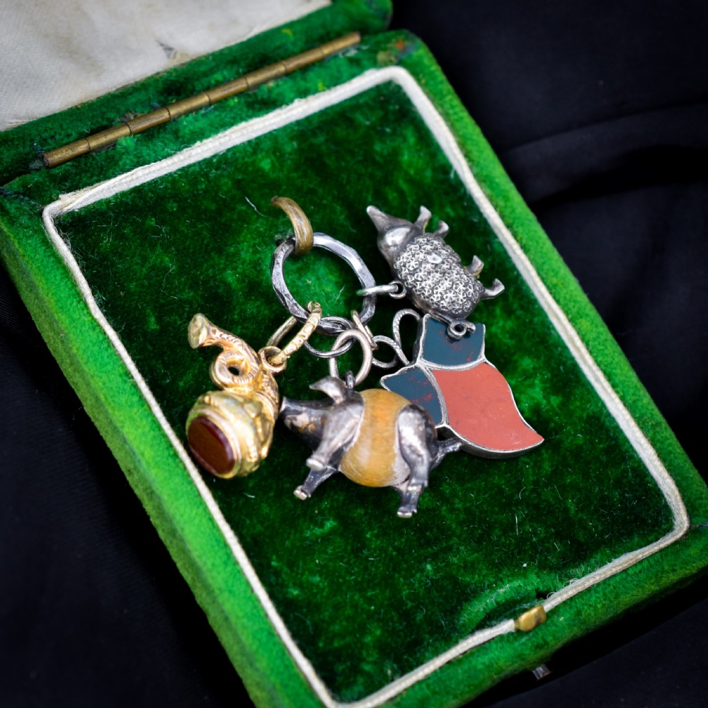 A cluster of antique silver and gold-gilt novelty charms, including pigs and a bugle, attached to a central metal split ring. View II