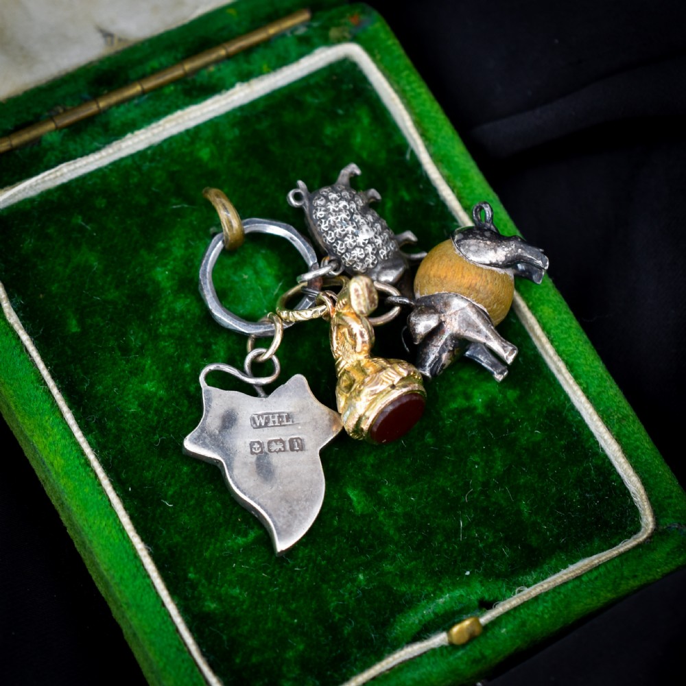 A cluster of antique silver and gold-gilt novelty charms, including pigs and a bugle, attached to a central metal split ring. View VII