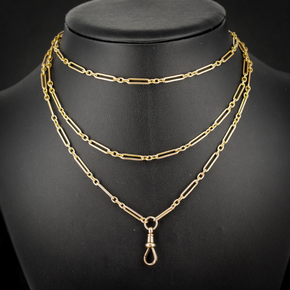 An antique long 9ct yellow gold paper link chain necklace layered around a black display bust with a swivel dog clip clasp.