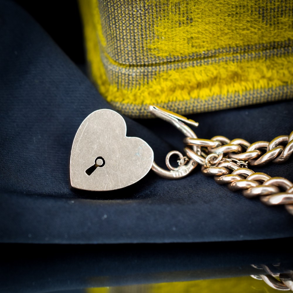 An antique 9ct rose gold curb chain bracelet featuring a heart padlock clasp and a central crescent moon and star motif set with seed pearls. View IV